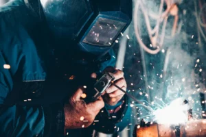 Técnico soldando en planta industrial con chispas de soldadura