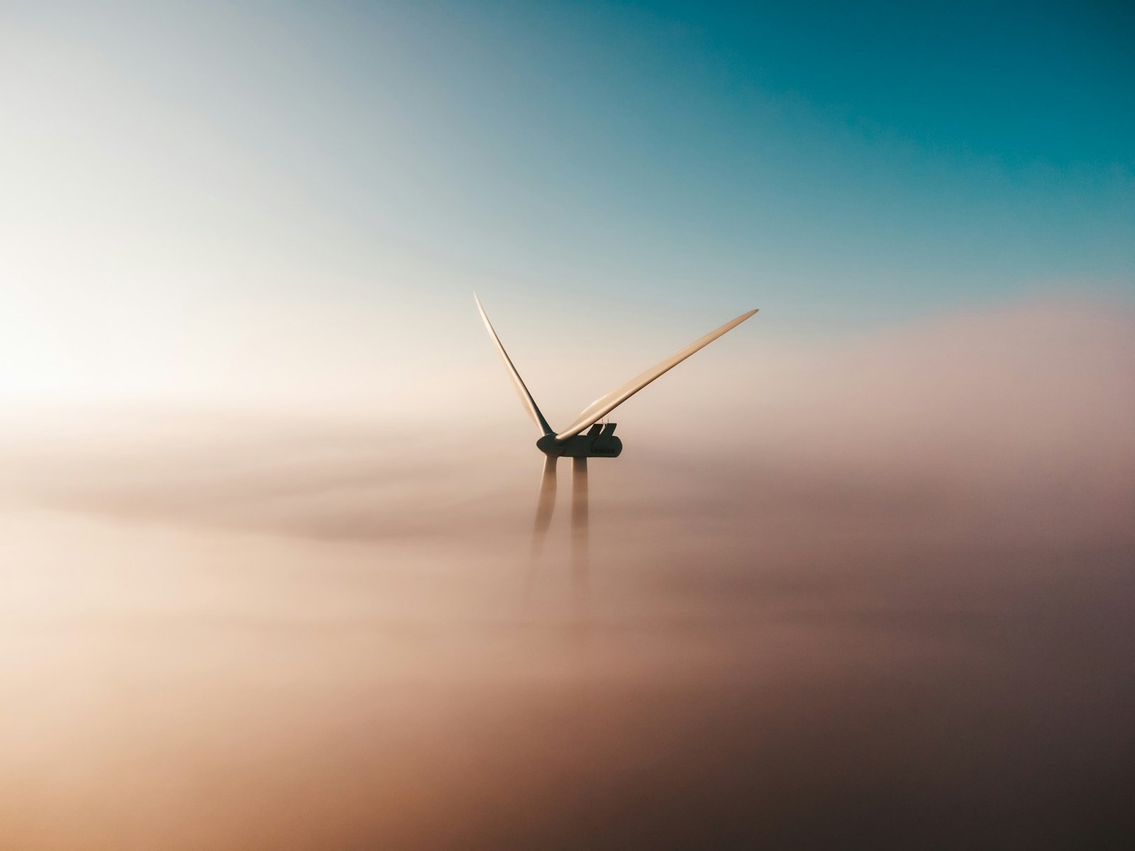 Turbina eólica emergiendo de la niebla al amanecer
