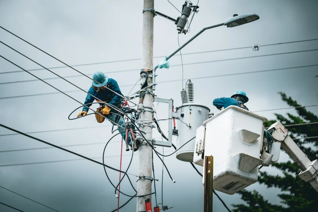 Técnicos linieros trabajando en poste de alta tensión con transformador, Costa Rica