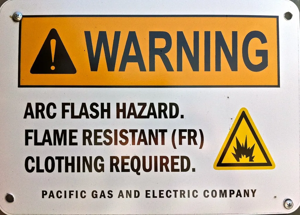 Letrero de advertencia de peligro por arco eléctrico que exige ropa resistente a la flama