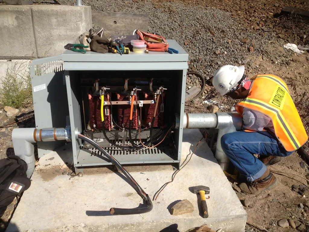 Técnico trabajando junto a un transformador tipo pedestal en una instalación eléctrica nueva